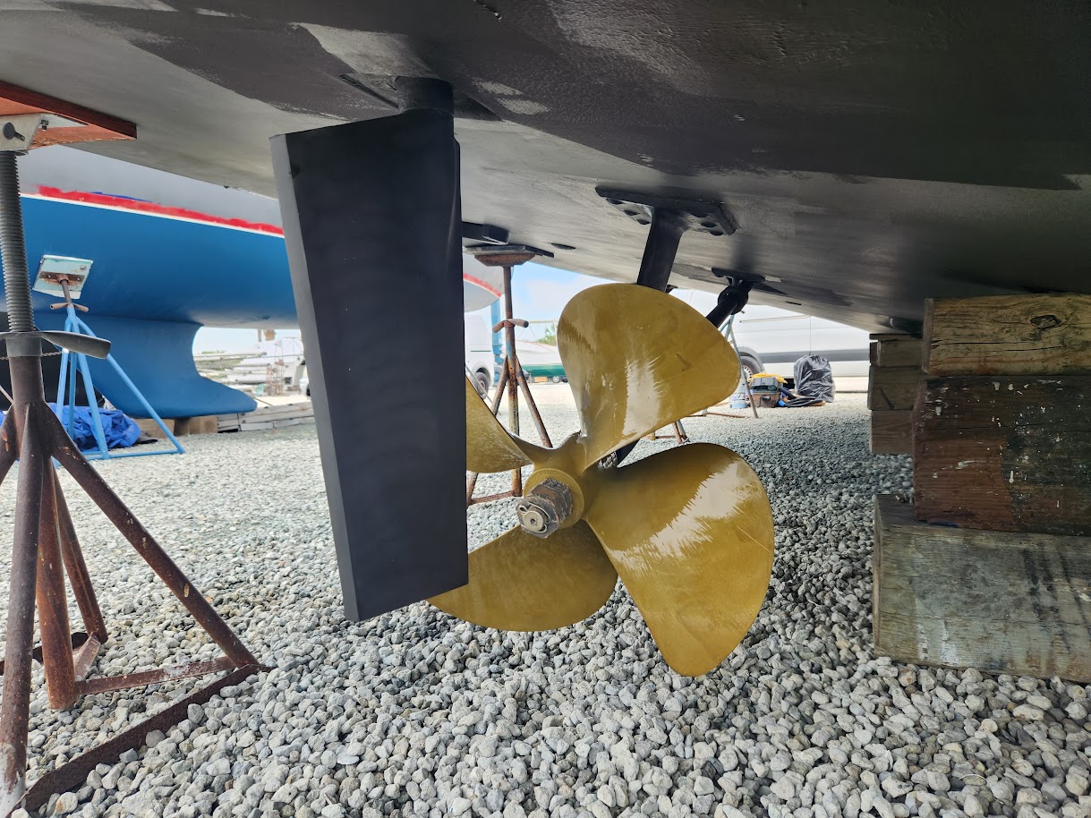 Propeller and rudder visible beneath a boat supported at a Southwest Florida boatyard