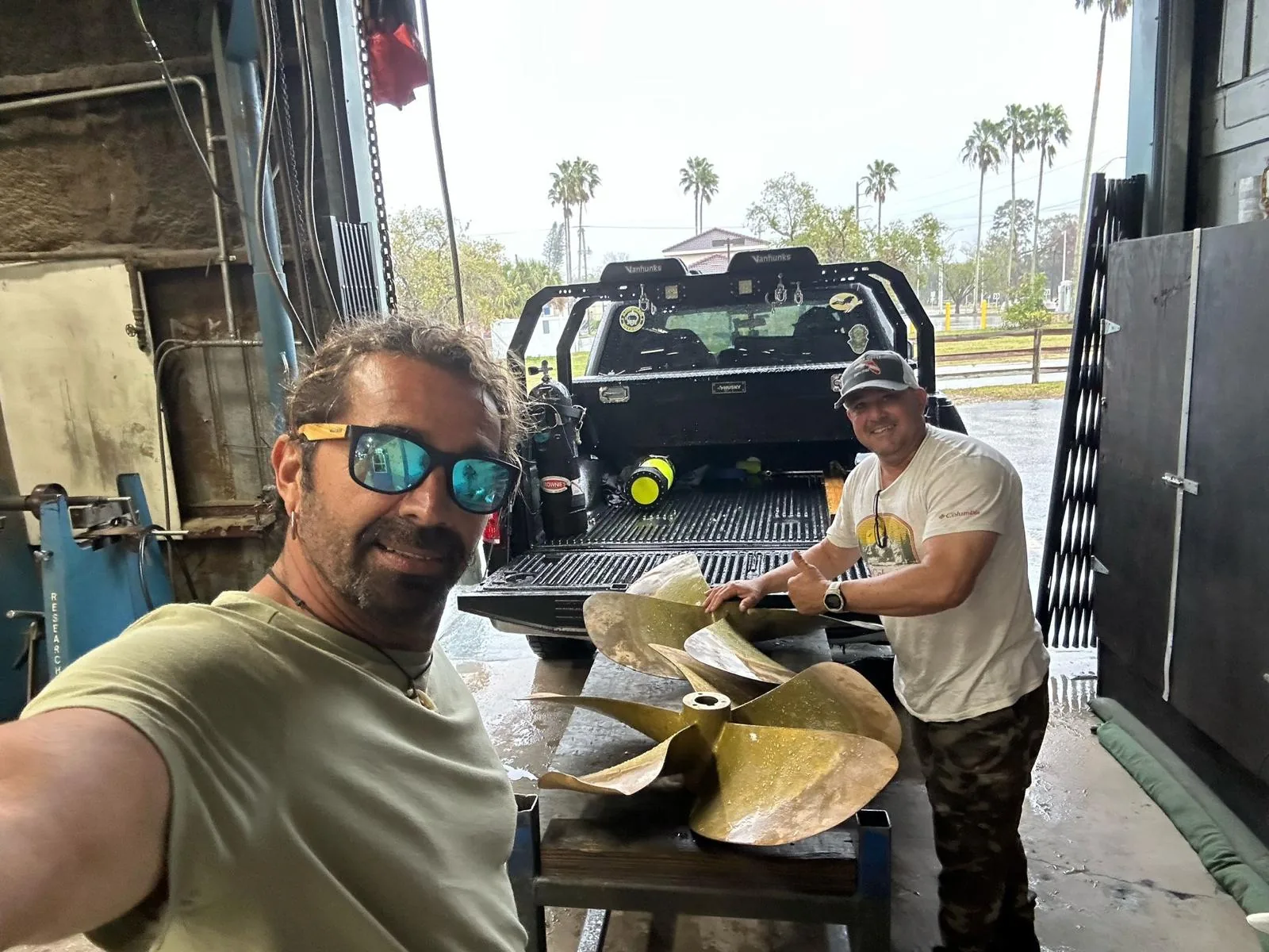 Bottom Time Dive Service team with boat propellers at the workshop